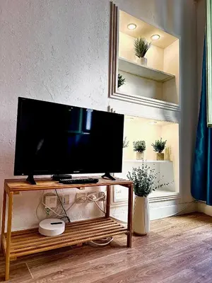a flat screen tv on a wooden stand in a living room at Romantique - NeaSpace Vieux Nice in Nice