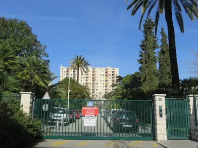 a gate with cars parked in a parking lot with a building at NICE NORD 2 PIECES CALMES,WIFI,CLIM,BALCON,PARKING in Nice