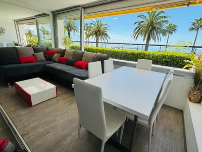 a living room with a couch and a table and chairs at Magnifique appartement les pieds dans l’eau à Nice in Saint-Laurent-du-Var