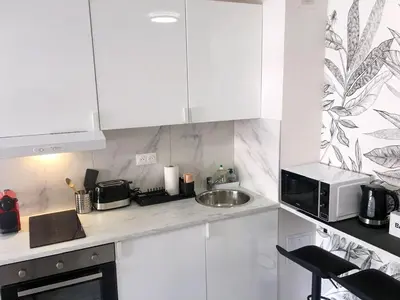 a kitchen with white cabinets and a sink and a microwave at Beachfront Studio on Promenade des Anglais in Nice