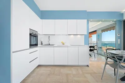 a kitchen with white cabinets and a dining room with a table at Balcon sur la Méditerranée in Nice