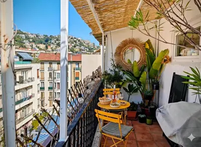 a balcony with a table and chairs on a building at Cozy roof terrace near Promenade des Anglais - AC in Nice