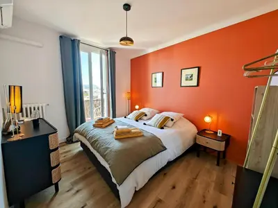 a bedroom with an orange wall with a bed and a window at Cozy roof terrace near Promenade des Anglais - AC in Nice