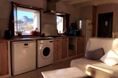 a kitchen with a washing machine and a couch at Maison de village vue montagne in La Gaude