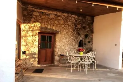 a patio with a table and chairs in front of a stone wall at Maison de village vue montagne in La Gaude