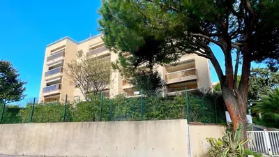 an apartment building with a fence and a tree at Eden Beach in Cagnes-sur-Mer