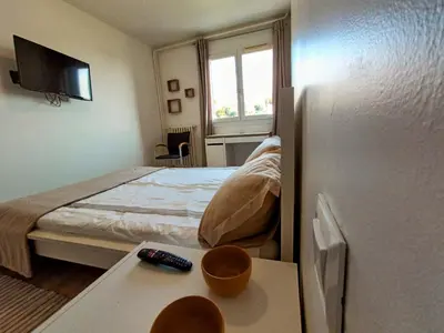 a bedroom with a bed and a table with a remote control at Private room in renovated apartment - Tram 1 min walk in Nice