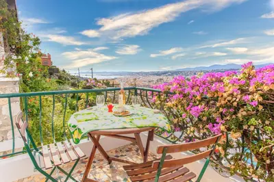 a table and chairs on a balcony with flowers at Beautiful villa with panoramic view over Nice in Nice