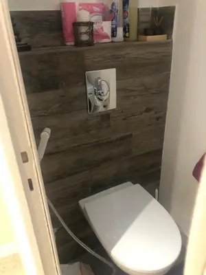 a white toilet in a bathroom with a wooden wall at Appart Nice Marguerite in Nice