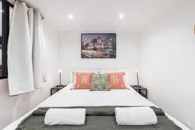 a white bedroom with a white bed with orange pillows at Spacious 2 Bdr Old Town Heart in Nice