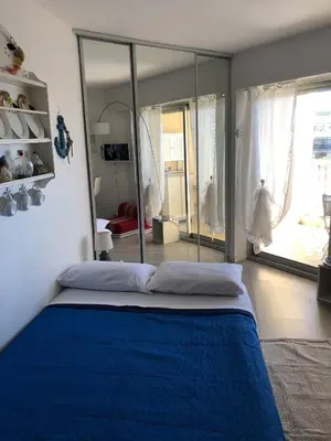 a bedroom with a blue bed and a large window at Charmant studio à Cros de Cagnes in Cagnes-sur-Mer