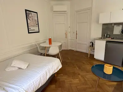 a room with a bed and a table and a kitchen at Negresco Residence Apartment with AC Promenade des Anglais in Nice