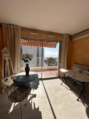 a living room with a table and a large window at Appartamento con vista Promenade in Nice