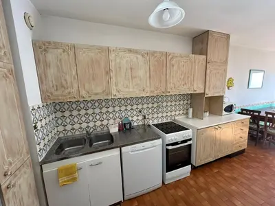 a kitchen with white appliances and wooden cabinets at Appartamento con vista Promenade in Nice