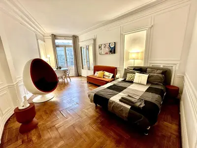 a bedroom with a bed and a chair in it at A Luxurious Apartment with AC on Promenade des Anglais in Nice
