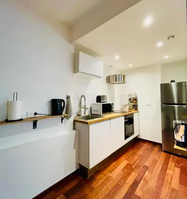 a kitchen with white cabinets and a wooden floor at Vieux-Nice : 2 pièces type loft in Nice