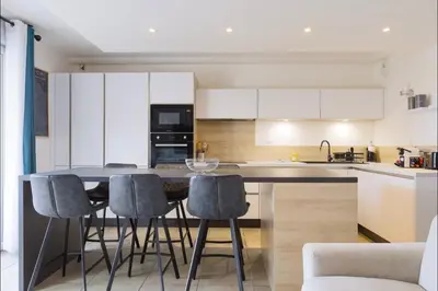 a kitchen with white cabinets and a table with stools at Q&R Renting - Appartement luxueux et Suites design- Parking AC Mer in Nice