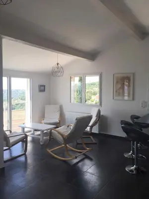 a living room with chairs and a table and windows at 3 pièces dans le ciel in Gattières