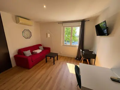 a living room with a red couch and a window at STUDIO CASSIN - next to tramway line 2 near airport in Nice
