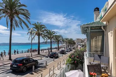 a street in front of a beach with palm trees at MY CASA - PONCHETTES - Independent House Promenade Des Anglais in Nice