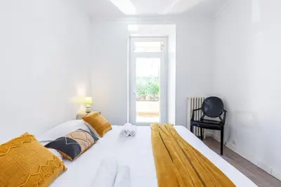 a bedroom with a large white bed with yellow sheets and a chair at MY CASA - PONCHETTES - Independent House Promenade Des Anglais in Nice