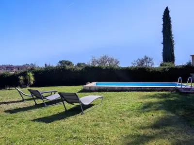 two chairs sitting in the grass next to a swimming pool at Villa Olivaie St Ange in La Gaude