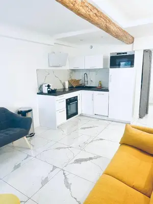 a kitchen with white cabinets and a yellow couch at T3 carré d’or plein centre in Nice