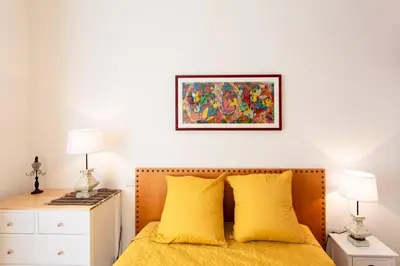 a bedroom with a bed with yellow pillows and a painting on the wall at L6 2Rooms 2mins walk from Negresco & Sea AC-Wifi in Nice