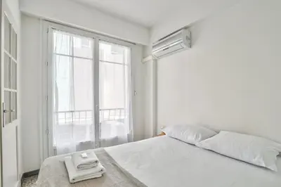 a white bedroom with a bed with a towel on it at L29 Lenval beach at 1min walk to Sea front AC Balcony in Nice
