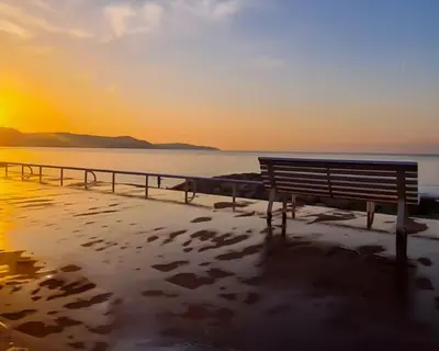 a bench on the beach with the sunset in the background at L39 Suite Promenade des Anglais, Vue Mer Terrasse&WIFI in Nice