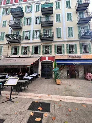 a large building with tables and chairs in front of it at Grimaldi Central AC 2 terraces Wifi 5mins SEA in Nice