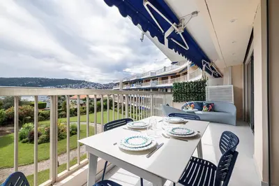 a white table and chairs on a balcony with a view at FEEL HOME - GRASSEUIL in Saint-Jean-Cap-Ferrat