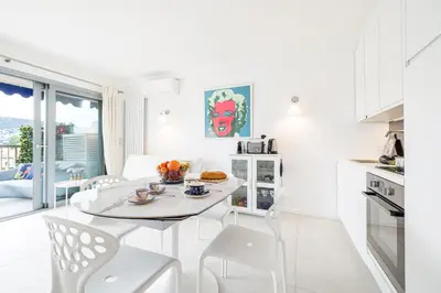 a white kitchen and dining room with a table and chairs at FEEL HOME - GRASSEUIL in Saint-Jean-Cap-Ferrat