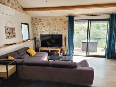 a living room with a brown couch and a television at Chaleureuse bergerie rénovée. in Tourrette-Levens