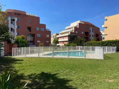 a white fence around a swimming pool in a city at Pretty Studio Swimming pool and Sea in Cagnes-sur-Mer